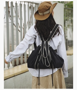 Outdoor shot showing back view of the large black canvas drawstring tote bag with cream stripes