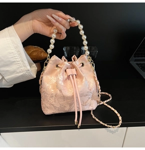 Detailed shot of pink bucket bag featuring 3D floral texture and elegant pearl handle