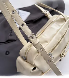 Detail of cream Boston bag with silver hardware and eyelet strap on a suit jacket
