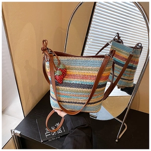 Detail of colorful striped woven bucket bag with leather strap and strawberry charms
