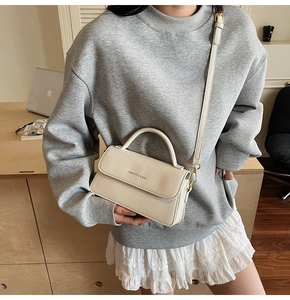 Close-up of cream white handbag with Fashion & Bags lettering and metallic buckle details