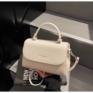 Detail of cream white leather handbag with litchi texture and metal buckle closure