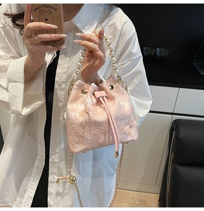 Close-up of pink bucket bag with floral lace embroidery and pearl handle details