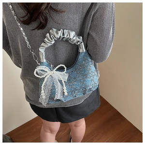 Detailed view of denim handbag with sparkling sequins and pearl bow accessory