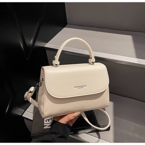 Detailed view of cream leather handbag showing lychee texture and silver hardware