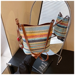 Detail of colorful woven bucket bag featuring leather strap and cute strawberry charms