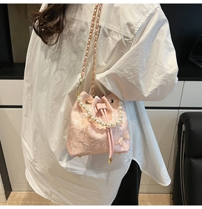 Close-up of pink bucket bag featuring lace floral embroidery and pearl handle strap