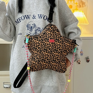 Detail of star-shaped leopard print crossbody bag with colorful woven handle and red logo