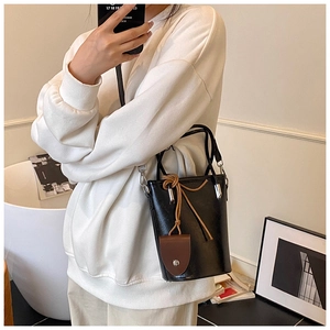 Detail of vintage bucket bag with brown drawstring knot and small hanging pouch charm