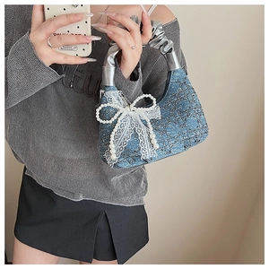 Detail of ruched silver handle and blue denim bag with lace bows and pearl accents