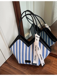 Blue and white striped canvas tote bag with V-shaped opening and black leather trim