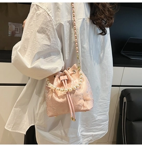 Detail of pink floral lace bucket bag featuring 3D butterfly accents and pearl handle