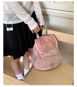 Detail of cute watermelon shaped backpack with pink body and green drawstring flap cover