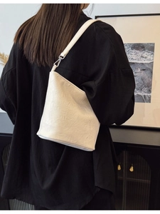 Minimalistische weiße Beuteltasche mit Faltenlederstruktur und schmalem Schultergurt