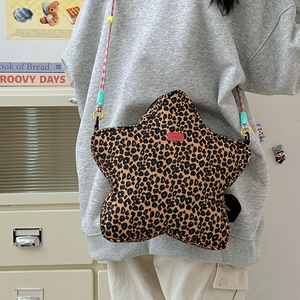 Detail of star-shaped leopard print crossbody bag with colorful woven strap and brand label