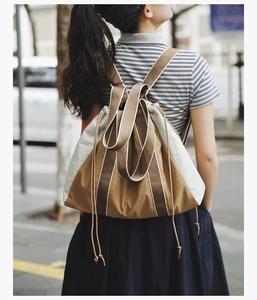 Outdoor shot of a casual canvas drawstring tote bag in khaki and off-white tones