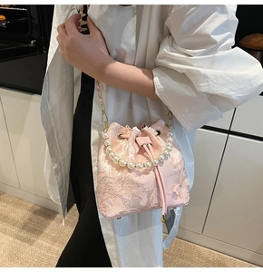 Detail of pink bucket bag with 3D floral embroidery and elegant pearl handle