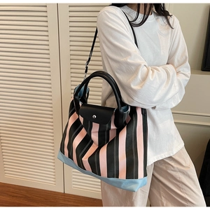 Detail of striped tote bag featuring pink and black vertical stripes with leather handles