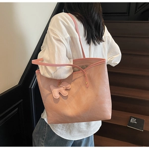 Pink tote bag with crocodile texture and dog charm shown on a shoulder in lifestyle scene