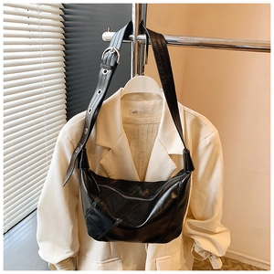 Détail du sac dumpling en cuir noir avec boucle argentée et large bandoulière