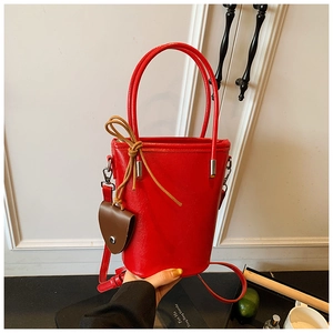 Close-up of a red glossy bucket bag with delicate handles and decorative charms