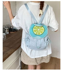 Detail of light blue nylon backpack featuring vibrant lemon slice motif and side drawstring pocket