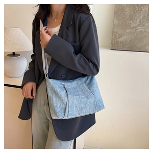 Detail of light blue canvas tote bag with pleated texture and Happy Sunday embroidery