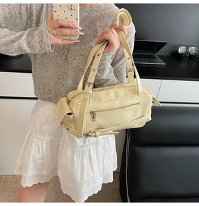 Detail of cream yellow leather bag with multiple zippers and decorative buckle straps