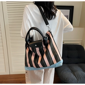 Detail of pink striped canvas tote bag showing the leather base and SORO brand engraving