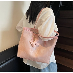 Detail of pink faux crocodile leather tote bag with a cute dog charm on casual shoulder strap