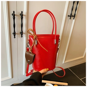 Detail of red faux leather bucket bag with smooth glossy finish and contrast drawstring