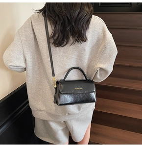 Detailed back view of a woman wearing a black vintage leather crossbody bag on stairs