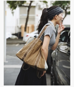 Detail of a large canvas tote bag with striped straps and drawstring closure