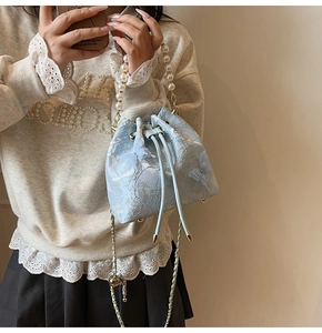 Close-up of light blue lace bucket bag with 3D butterfly appliqués and pearl handle