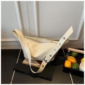 Détail du sac beige avec bandoulière à œillets et boucle argentée surdimensionnée