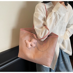 Pink croc-embossed large tote bag with cute dog pendant shown on a model in white shirt