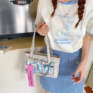 Detailansicht der grauen Itabag mit Sichtfenster für Anime-Pins und Herz-Kette