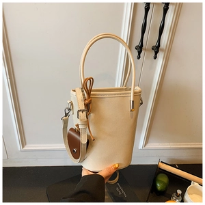 Detail of a creamy white bucket bag showing the sleek leather texture and slim top handles