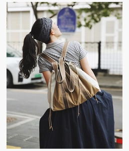Detail of canvas drawstring tote bag featuring vertical stripes and brown accents in nature