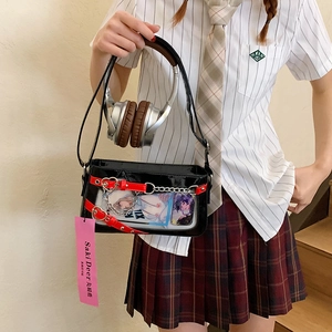 Détail du sac Ita noir avec fenêtre transparente, breloque coeur et lanière rouge