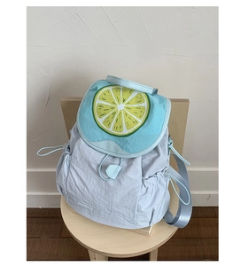 Detail of light blue nylon backpack featuring a bright yellow lemon slice print on the flap