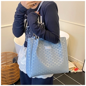 Vue détaillée d'un sac cabas bleu clair avec texture gaufrée et poignée dorée