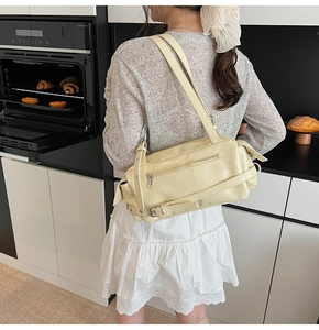 Detail view of cream yellow leather pillow bag with silver zipper and buckle accents