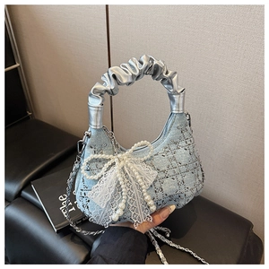 Close-up of light blue denim bag with rhinestone grid, lace bow, and silver handle