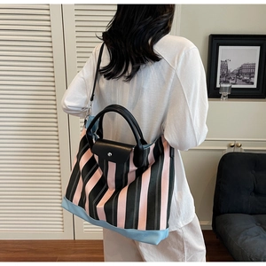 Close-up of pink striped tote bag showing durable leather bottom and embossed SOCO logo