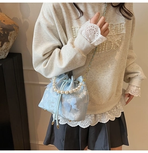 Detail of light blue bucket bag with 3D butterfly embroidery and pearl handle