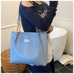 Détail du sac cabas bleu clair avec chaîne dorée et motifs de logo en relief