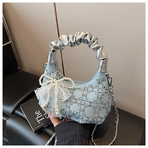 Detail of light blue denim bag featuring silver rivet quilting and pearl bow charm