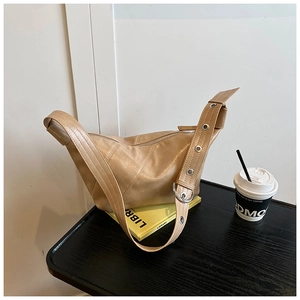 Détail du sac croissant kaki avec des œillets argentés sur la large bandoulière