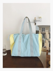 Detail of blue and yellow nylon tote bag with drawstring closure hanging on wall